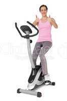 Beautiful woman gesturing thumbs up on stationary bike