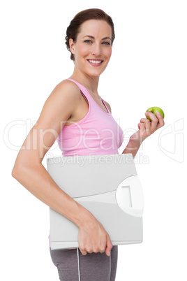 Portrait of a young woman with weight scale and apple