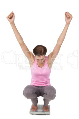 Full length of a young woman cheering on weight scale