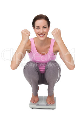 Portrait of a young woman cheering on weight scale