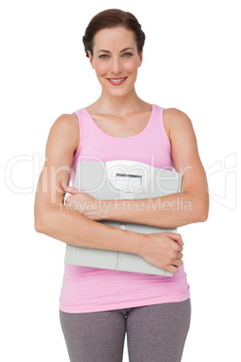 Portrait of a smiling young woman with weight scale
