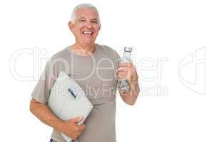 Cheerful senior man with water bottle and scales