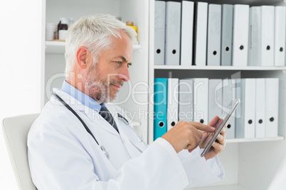 Concentrated doctor using digital tablet at medical office