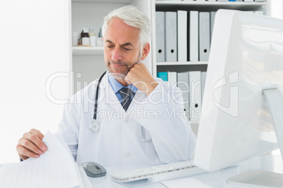 Mature male doctor with computer at medical office
