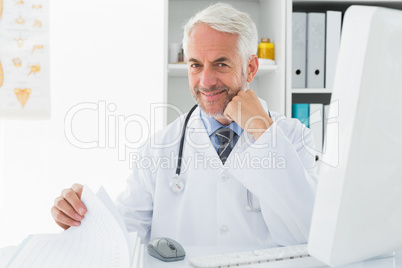 Mature male doctor with computer at medical office