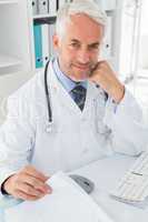 Mature male doctor at desk in the medical office