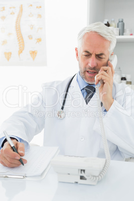 Male doctor writing reports while on call