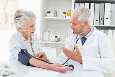 Doctor taking the blood pressure of his retired patient