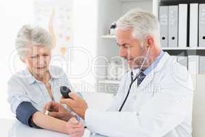 Doctor taking the blood pressure of his retired patient