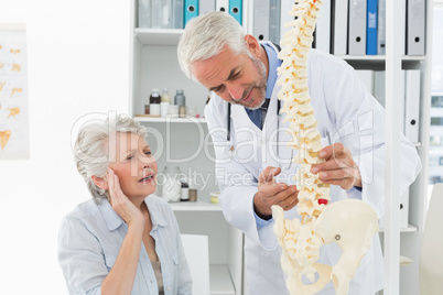 Male doctor explaining the spine to senior patient
