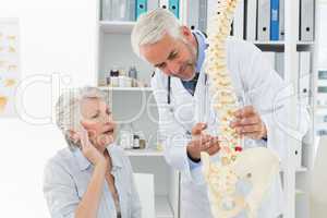 Male doctor explaining the spine to senior patient