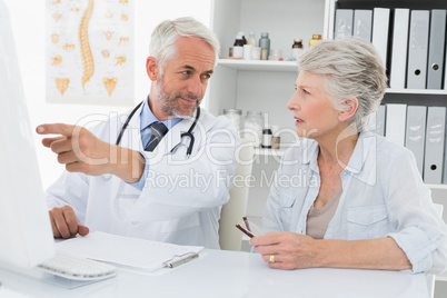 Doctor with female patient reading reports on computer