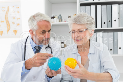 Doctor showing stress buster balls to senior patient