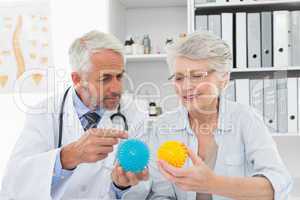 Doctor showing stress buster balls to senior patient