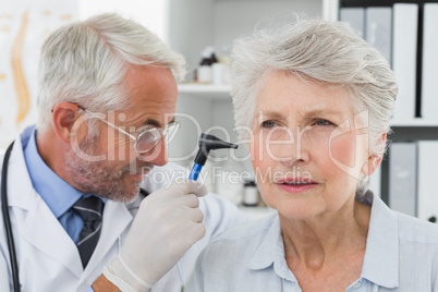 Doctor examining senior patient's ear
