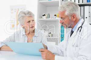 Male doctor with female patient reading reports