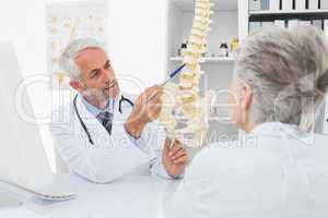 Male doctor explaining the spine to senior patient