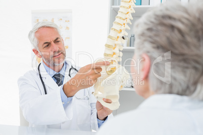 Male doctor explaining the spine to senior patient