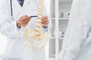 Mid section of doctor explaining the spine to patient