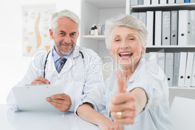 Happy senior patient gesturing thumbs up with doctor