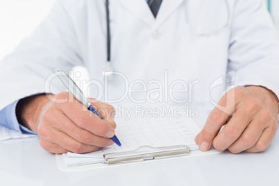 Mid section of a doctor writing on clipboard