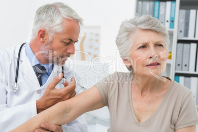 Male doctor injecting senior patient