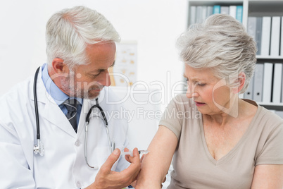 Male doctor injecting senior female patient