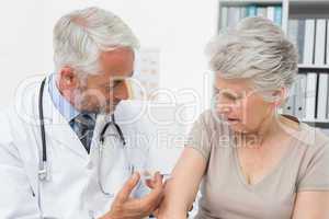Male doctor injecting senior female patient