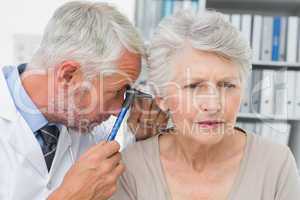 Close-up of a male doctor examining senior patient's ear