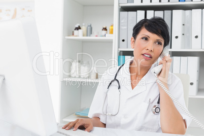 Doctor using computer and telephone