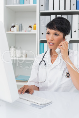 Concentrated doctor using computer and telephone