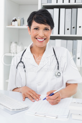 Portrait of a smiling doctor writing on clipboard