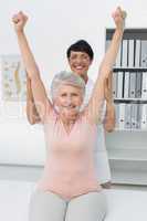 Female physiotherapist with senior woman raising hands