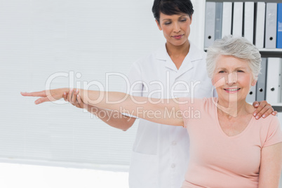 Physiotherapist assisting senior woman to stretch her hand