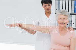 Physiotherapist assisting senior woman to stretch her hand