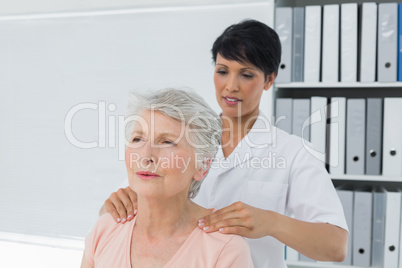 Chiropractor massaging a senior womans shoulder