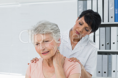 Chiropractor looking at senior woman with neck pain