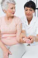 Female physiotherapist examining a senior patients hand