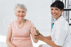 Female doctor fixing wrist brace on senior patients hand