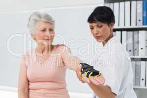 Female doctor fixing wrist brace on senior patients hand