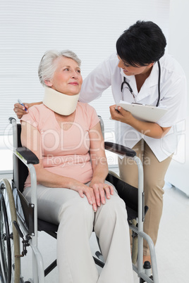 Doctor talking to senior patient in wheelchair with cervical col