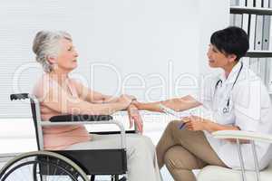 Doctor talking to a senior patient in wheelchair