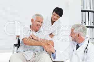 Happy senior patient and doctor shaking hands