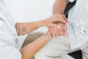Mid section of a doctor holding patients hand