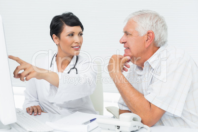 Doctor with male patient reading reports on computer