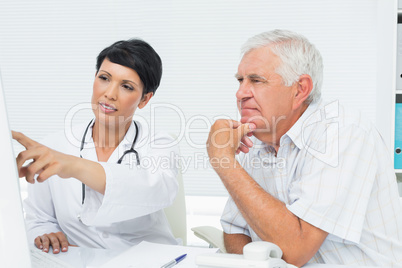 Doctor with male patient reading reports on computer