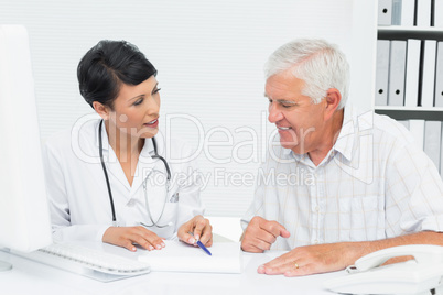 Female doctor with male patient reading reports