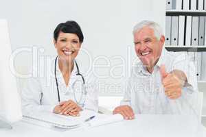 Happy senior patient gesturing thumbs up with doctor