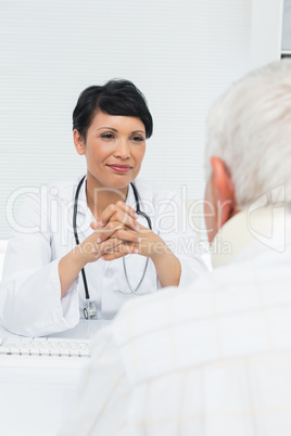 Young female doctor attentively listening to senior patient