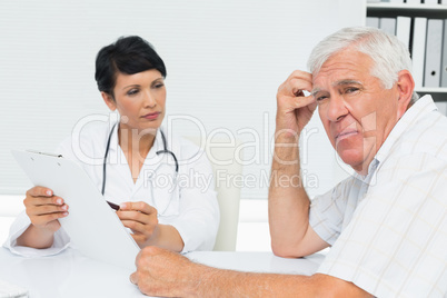 Doctor showing reports to worried senior patient
